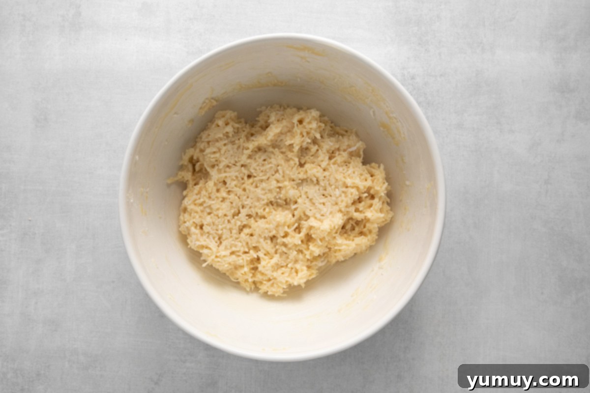 Creamy Coconut Delights 7 The combined coconut truffle mixture, now a sticky and cohesive mass, resting in a white mixing bowl.