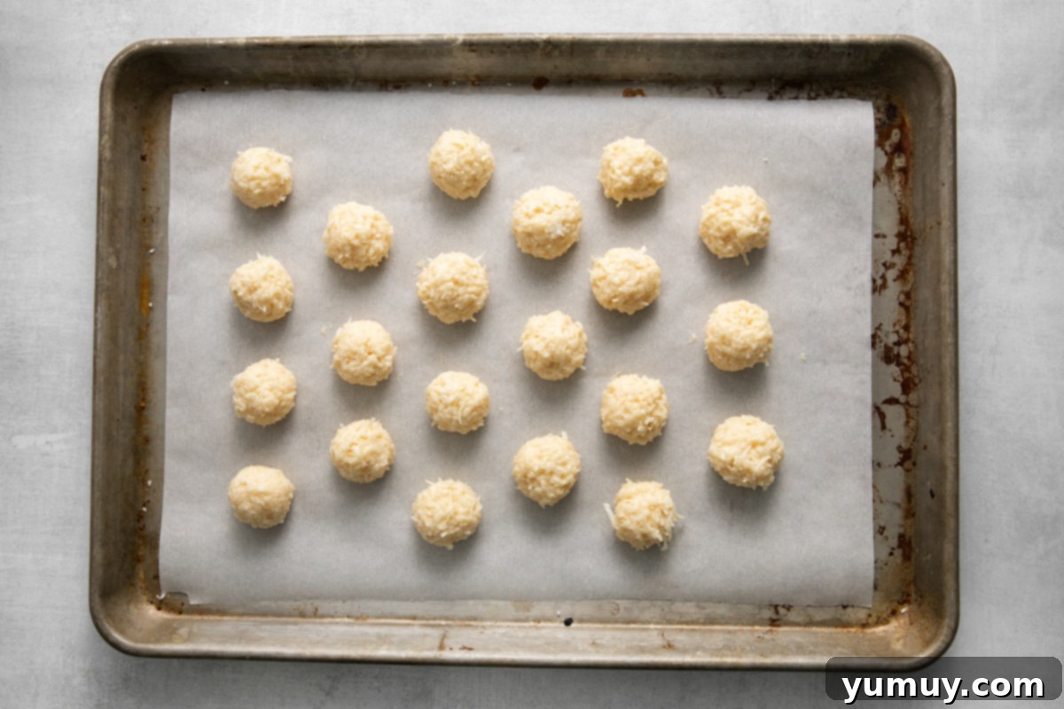 Creamy Coconut Delights 8 Twenty-one perfectly shaped, undipped coconut truffles neatly arranged on a parchment-lined baking sheet, ready for chilling.