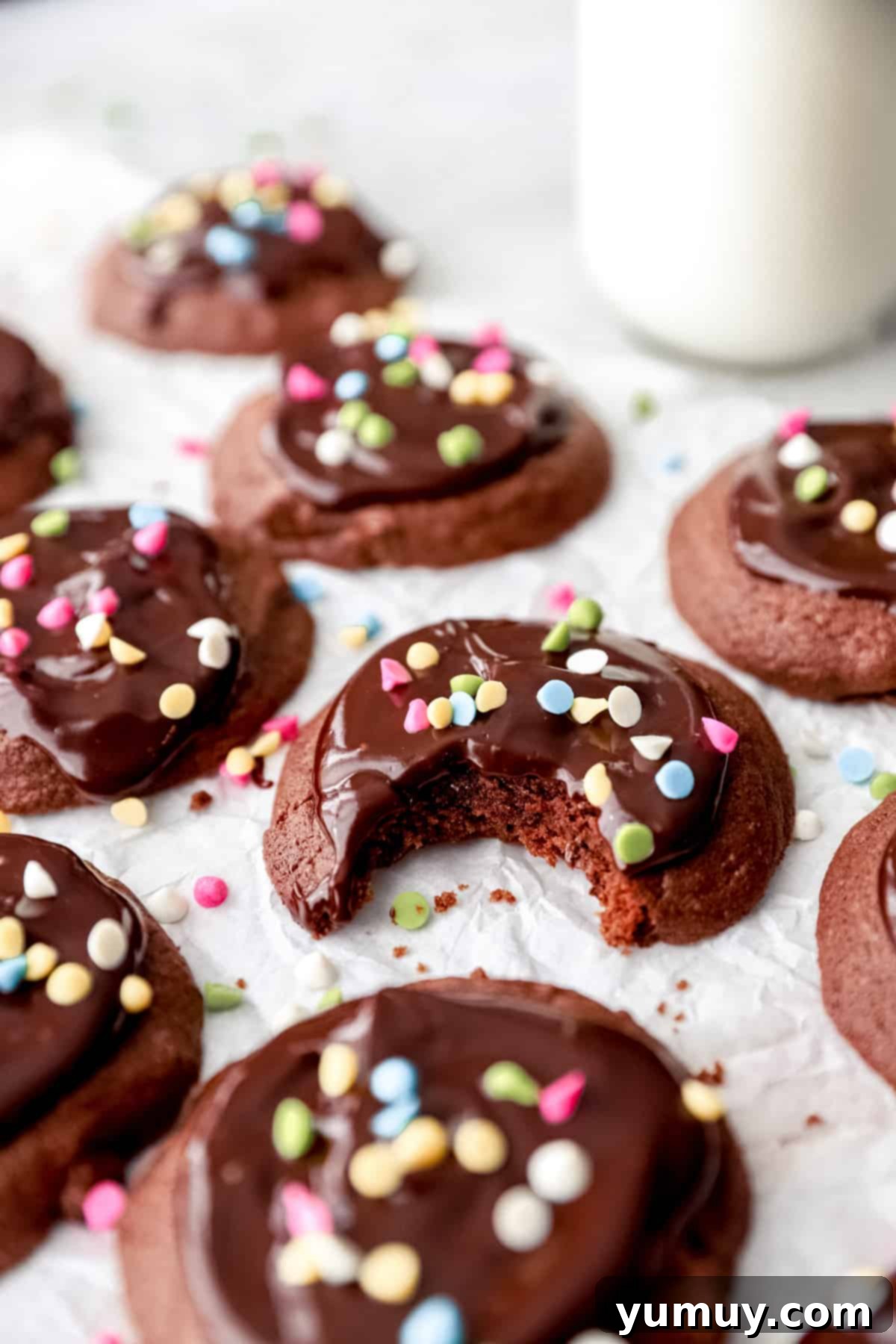 A bitten cosmic brownie cookie on parchment paper with more cookies.