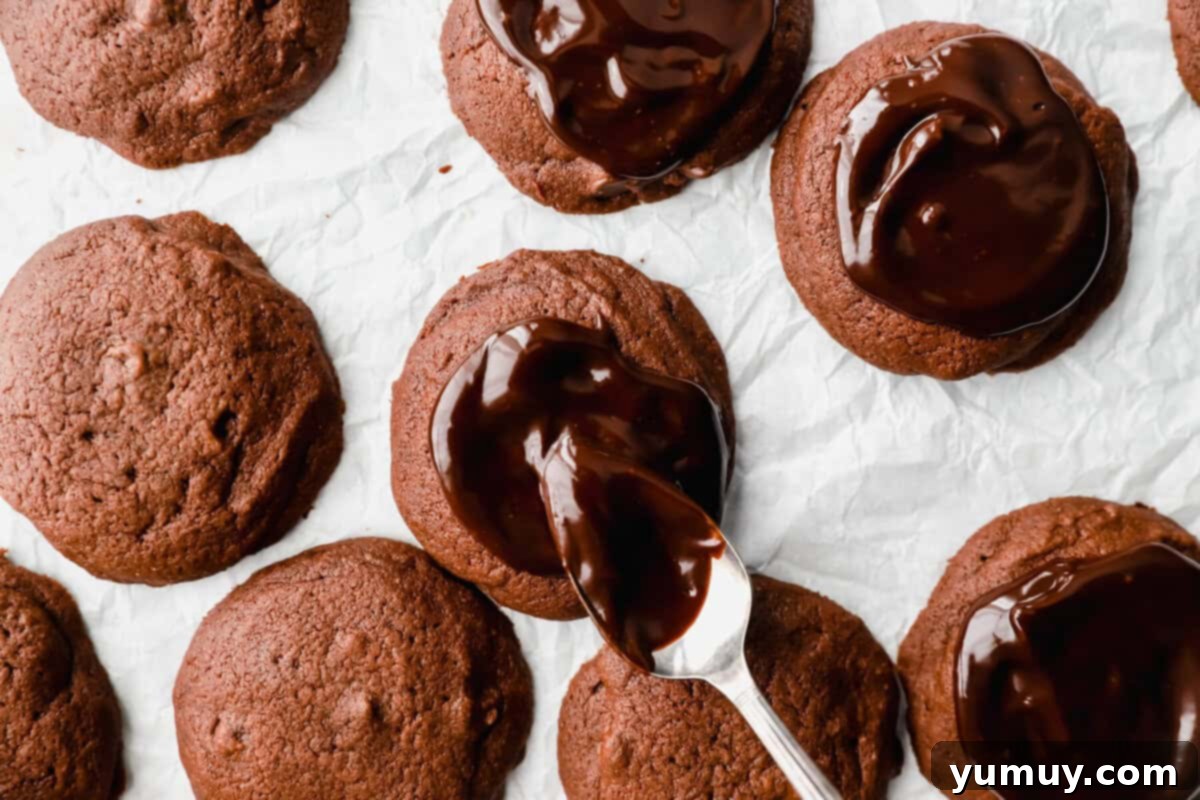 A spoon drizzling ganache over cosmic brownie cookies.