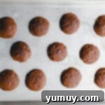 11 baked cosmic brownie cookies on a baking sheet.