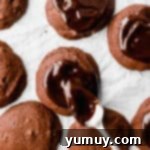 A spoon drizzling ganache over cosmic brownie cookies.