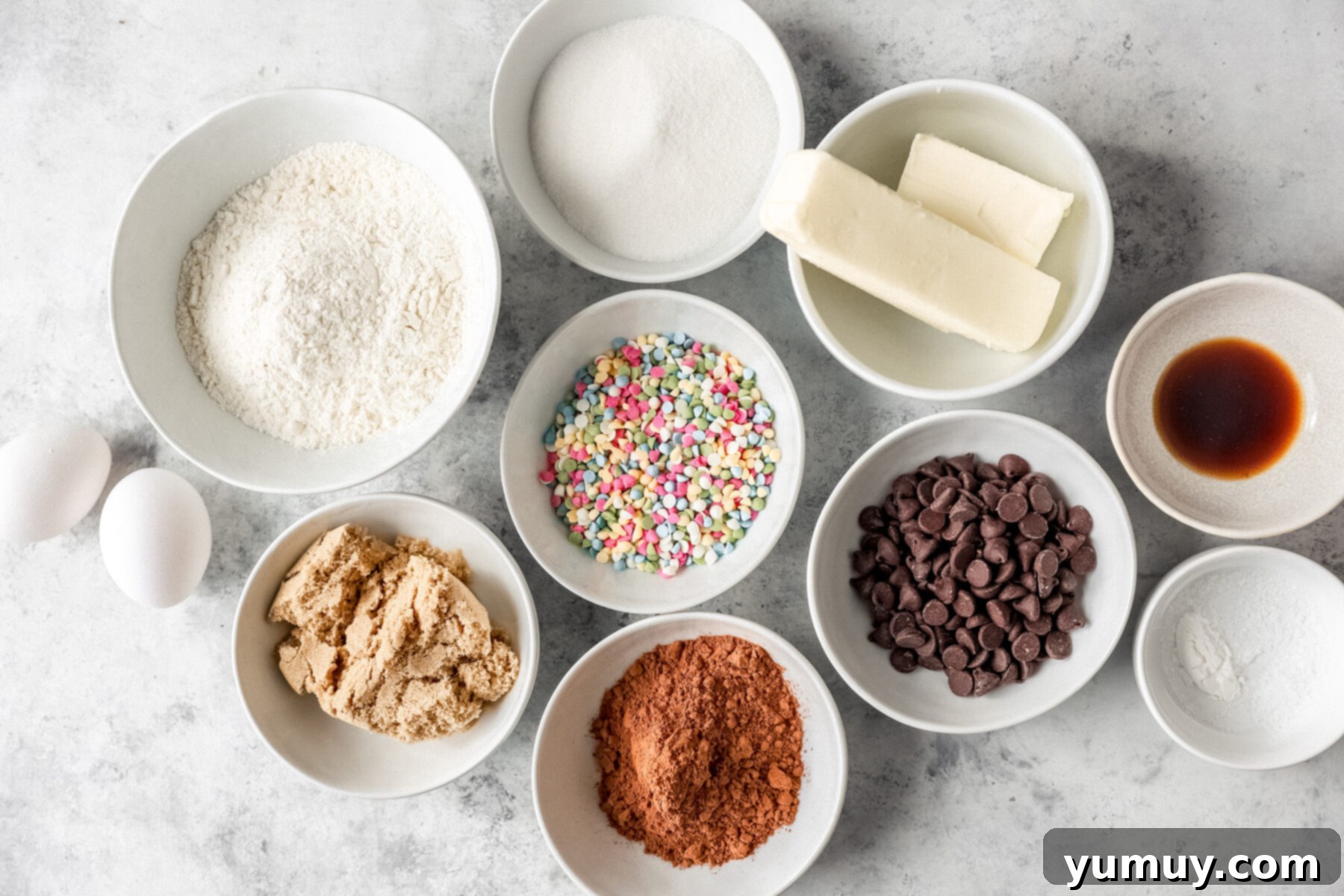 Overhead view of ingredients for cosmic brownie cookies in white bowls.