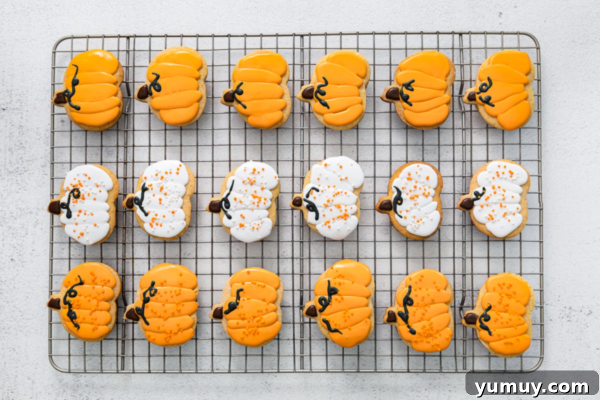 frosted pumpkin sugar cookies lined up on a cooling rack