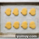 pumpkin shaped sugar cookies lined up on a baking tray