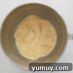 eggs and vanilla added to creamed butter, sugar, and maple syrup in a stainless mixing bowl.