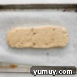 maple pecan biscotti dough patted into a 10x3 rectangle on a baking sheet.