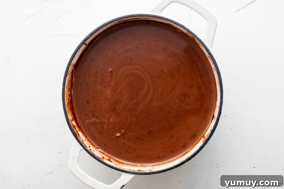 Overhead view of the Mexican hot chocolate simmering gently in a white Dutch oven, perfectly combined and heated.