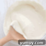 melted white chocolate in a bowl with a wooden spoon.