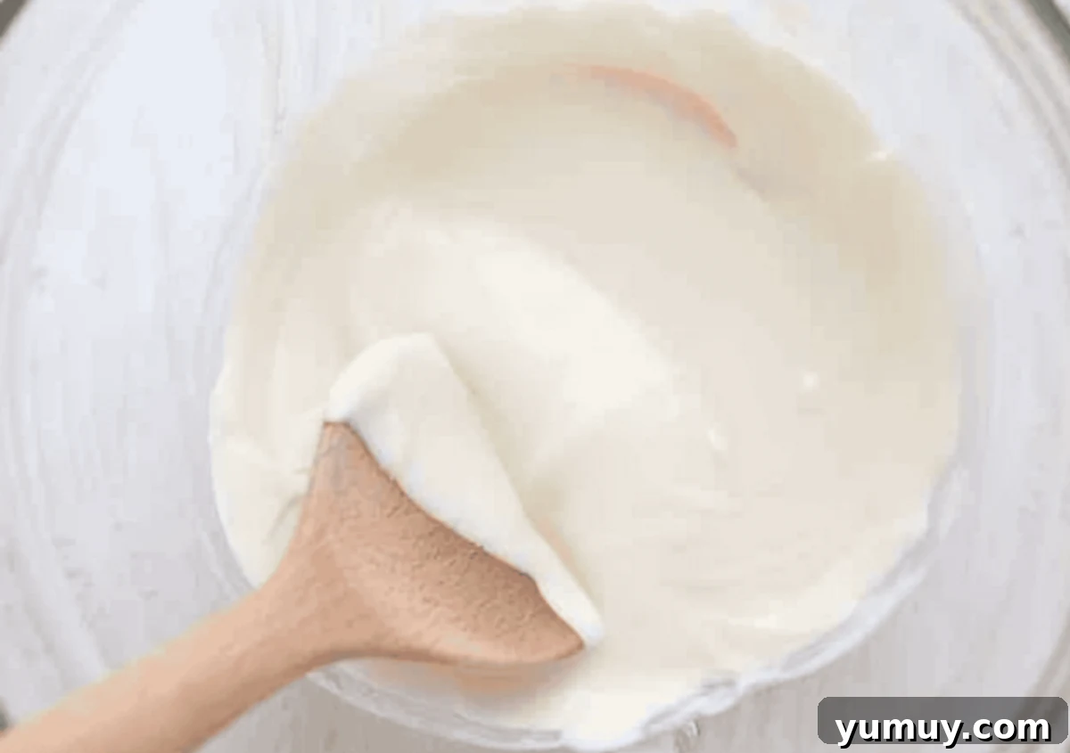 melted white chocolate in a bowl with a wooden spoon.