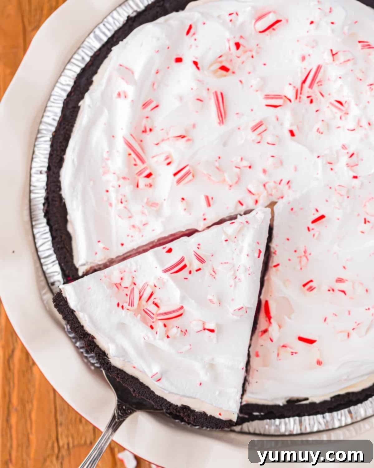 Frosty Peppermint Delight 4 An overhead shot of a cake server gracefully removing a slice of homemade peppermint pie, highlighting its creamy texture and festive topping.