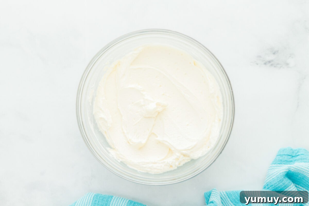 Winged Whimsy Cake 10 Overhead view of the light and fluffy homemade buttercream frosting in a white mixing bowl, ready for decorating the airplane cake.