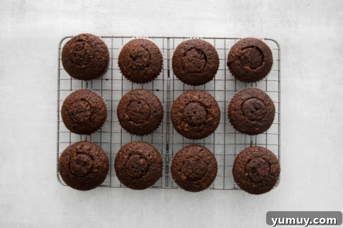 Twelve perfectly filled Kahlua cupcakes patiently resting on a wire rack, awaiting their delightful frosting.