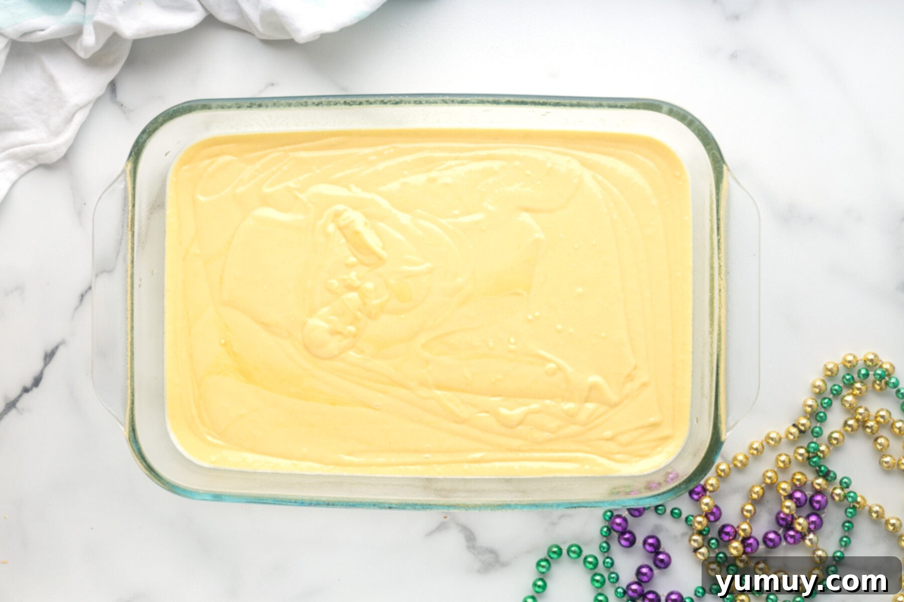 Mardi Gras King Cake Poke 13 Yellow cake mix batter neatly poured into a rectangular cake pan, ready to be placed in the oven for baking.
