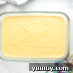 Mardi Gras King Cake Poke 6 Baked yellow cake in a rectangular cake pan, presenting a golden-brown top, ready for the next step of making a poke cake.