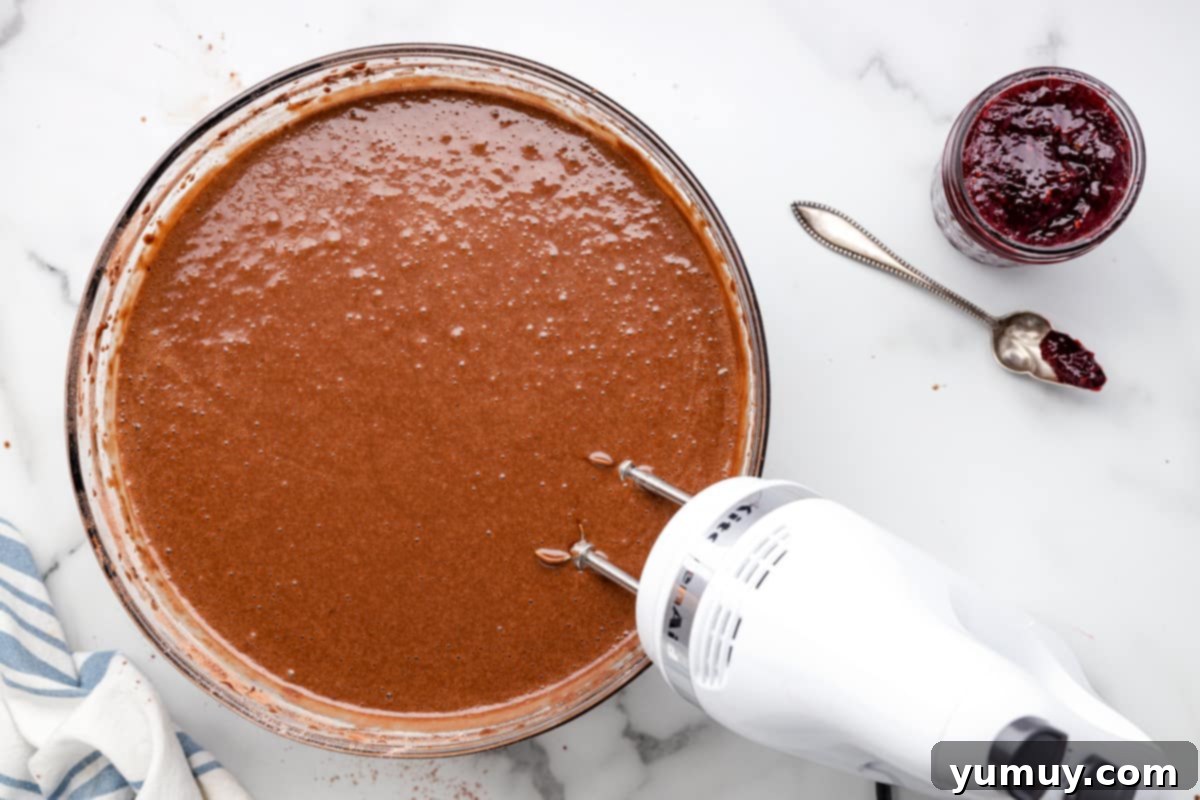 Dark Chocolate Raspberry Gateau 11 chocolate cake batter in a glass bowl with a hand mixer.