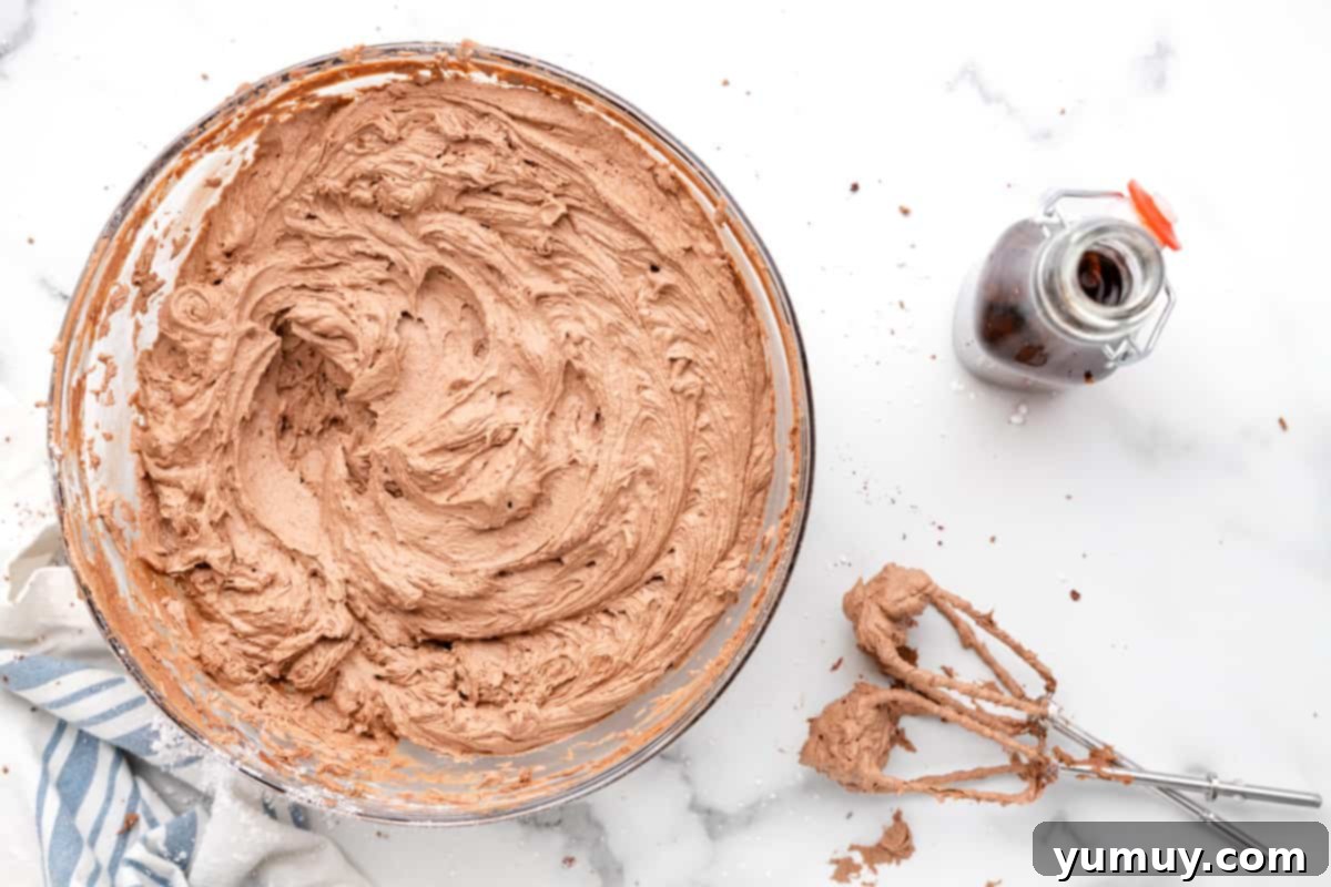 Dark Chocolate Raspberry Gateau 14 chocolate buttercream in a glass bowl next to hand mixer beaters.