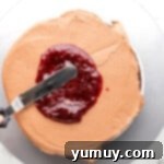 Dark Chocolate Raspberry Gateau 9 raspberry preserves spread over chocolate frosting and chocolate cake on a gray cake board.