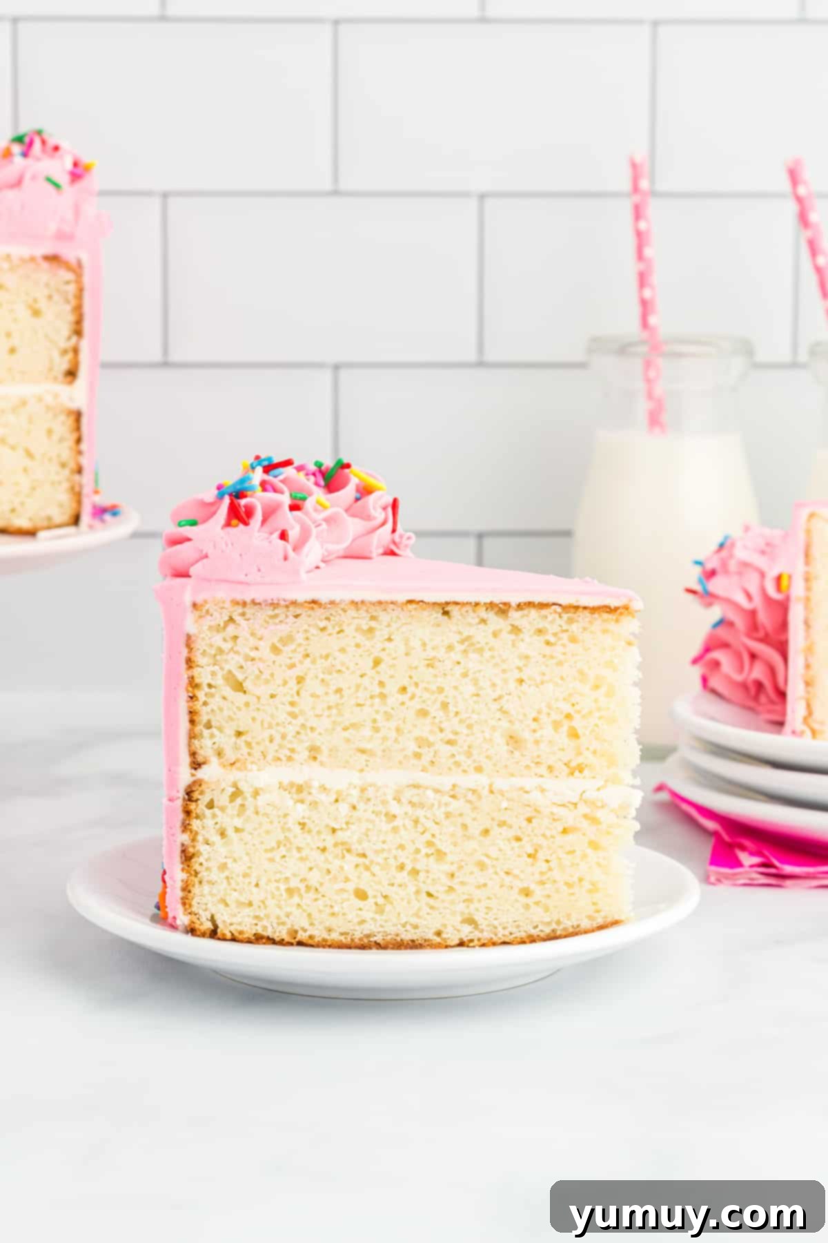 side view of a slice of doctored white cake mix cake on a white plate, showcasing its moist texture and perfect frosting.