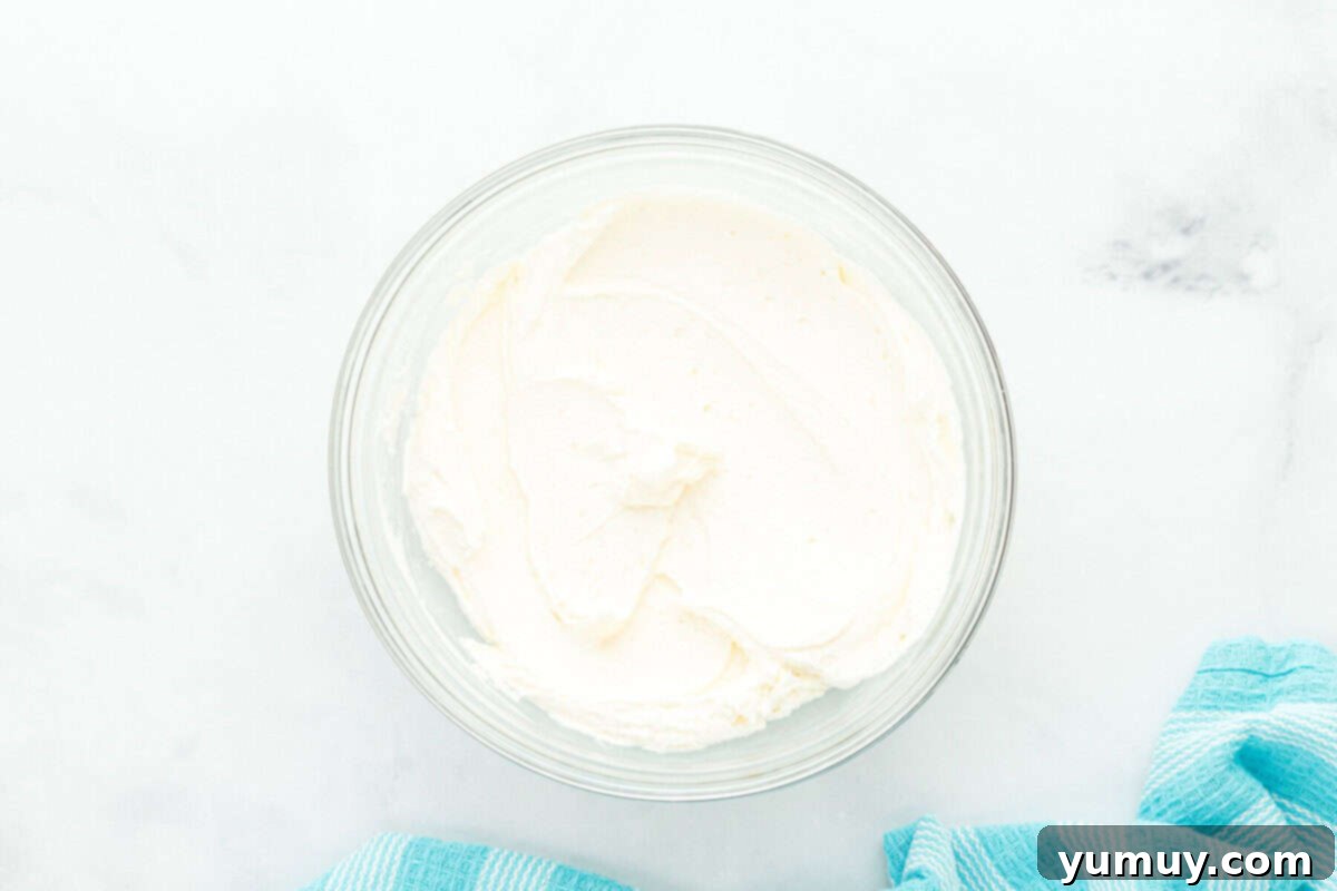 creamy, fluffy buttercream frosting for doctored white cake mix in a clear glass bowl, ready for application.