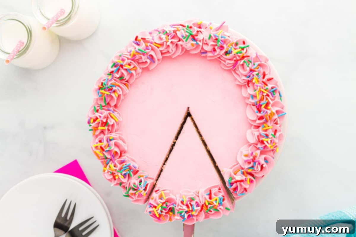 overhead view of a cake server gracefully removing a slice from a vibrant pink frosted doctored white cake mix cake, adorned with sprinkles, showcasing its delicious layers.