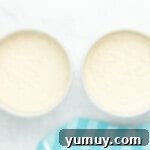 smooth doctored white cake mix batter evenly distributed in two round baking pans.