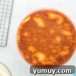 stacked doctored white cake mix layers on a white cake stand, ready for crumb coating.