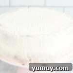 crumb coated doctored white cake mix cake on a white cake stand, prepared for final frosting.