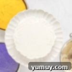 Mardi Gras Birthday Fiesta 11 Frosted green layer of Mardi Gras birthday cake on a white cake stand, demonstrating even frosting application.