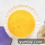 Mardi Gras Birthday Fiesta 12 Yellow Mardi Gras cake layer stacked precisely on top of a frosted green layer on a white cake stand, forming the second tier.