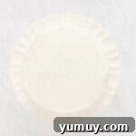 Mardi Gras Birthday Fiesta 13 Crumb coated Mardi Gras birthday cake on a white cake stand, showing the initial layer of frosting to seal in crumbs.