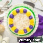Mardi Gras Birthday Fiesta 14 Overhead view of a beautifully decorated Mardi Gras birthday cake on a white cake stand, adorned with colorful frosting and sprinkles.