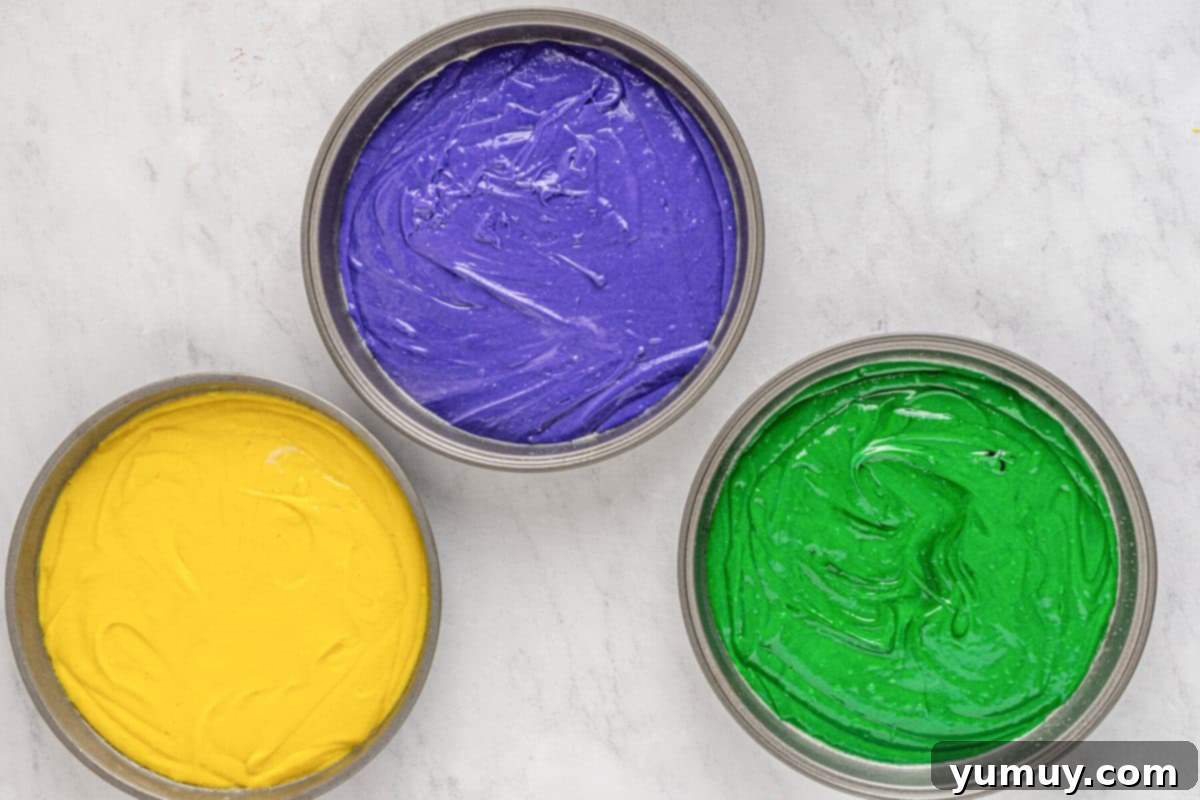 Mardi Gras Birthday Fiesta 17 Yellow, purple, and green Mardi Gras cake batter neatly poured into separate round cake pans, ready to be baked.