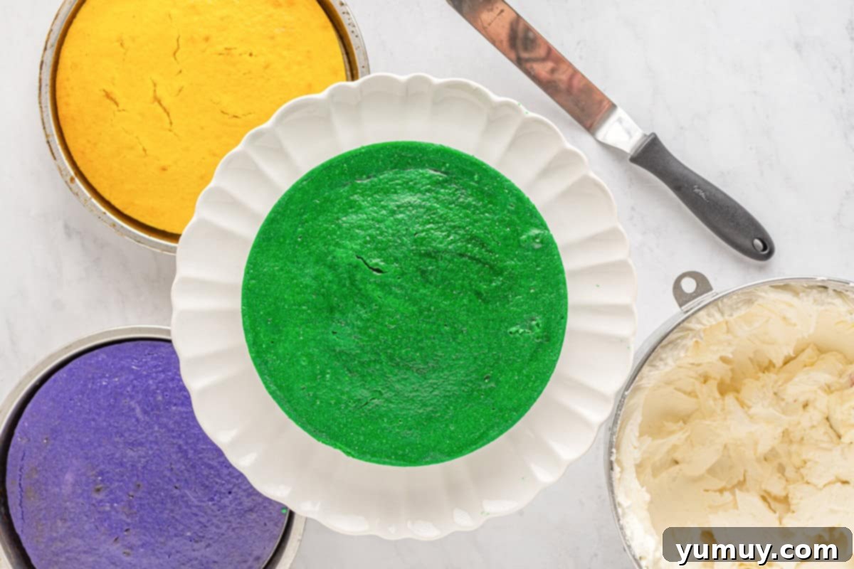 Mardi Gras Birthday Fiesta 19 The green Mardi Gras cake layer positioned on a white cake stand, serving as the foundation for the layered cake.