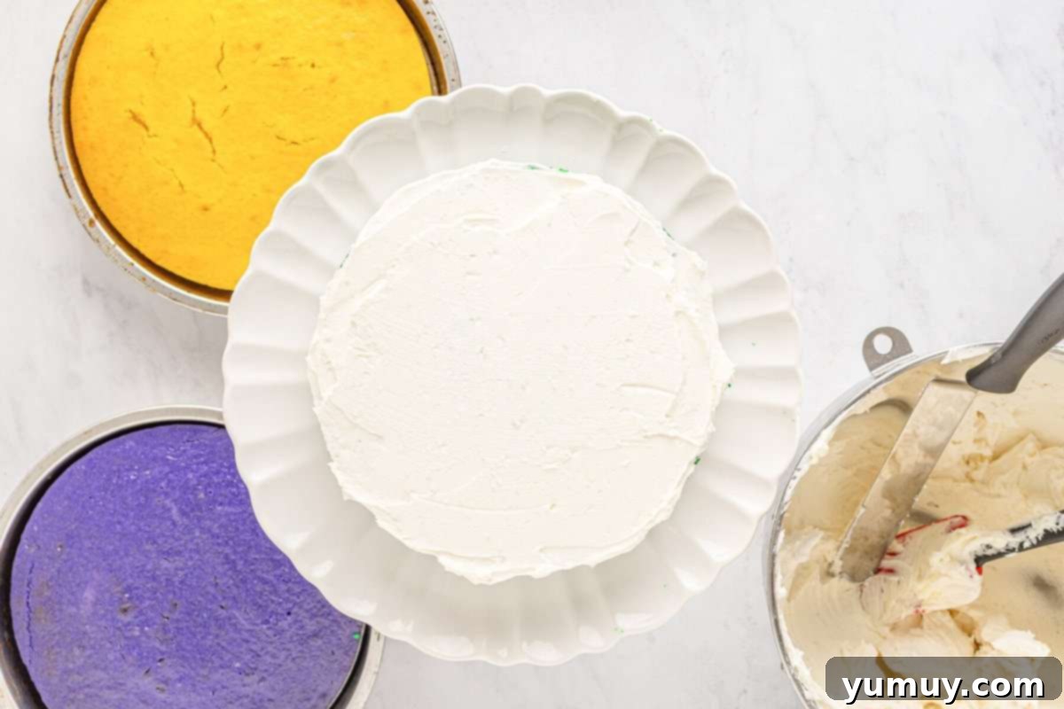 Mardi Gras Birthday Fiesta 20 A frosted green layer of Mardi Gras birthday cake on a white cake stand, showcasing the even application of buttercream.