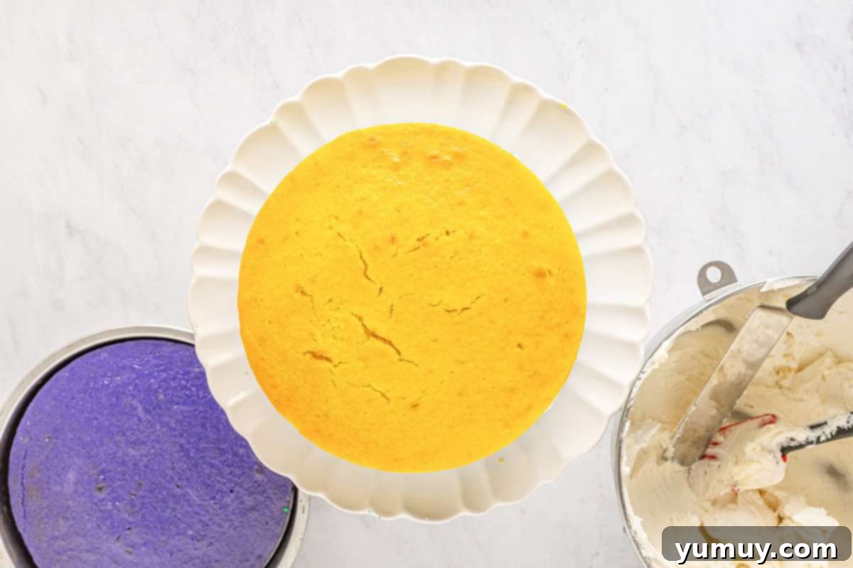 Mardi Gras Birthday Fiesta 21 The yellow Mardi Gras cake layer stacked precisely on top of the frosted green layer on a white cake stand, creating a multi-colored base.