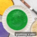 Mardi Gras Birthday Fiesta 10 Green Mardi Gras cake layer securely placed on a white cake stand, ready for frosting.