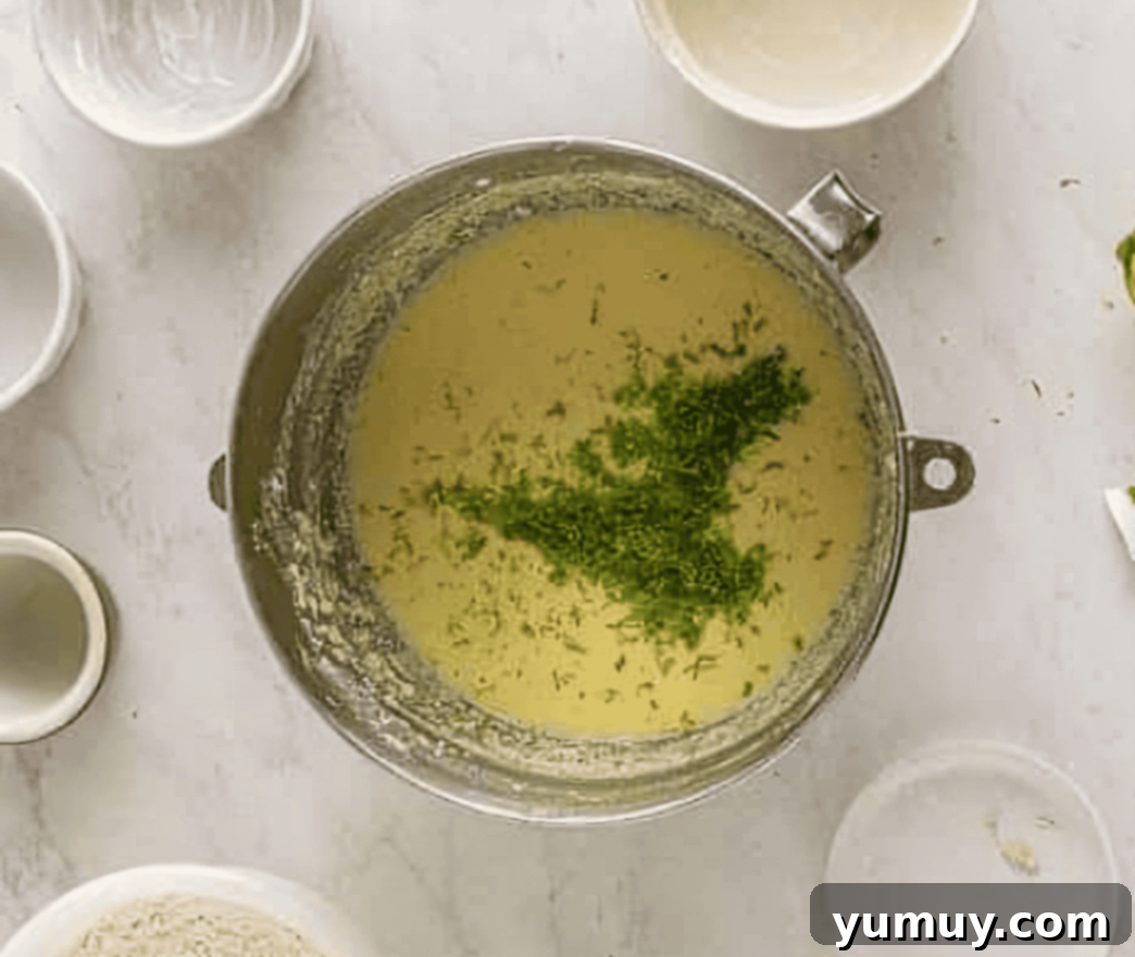 Cinco de Mayo Fiesta Cupcakes 6 lime zest added to cupcake batter in a stainless steel mixing bowl, showing the creamy wet ingredients.
