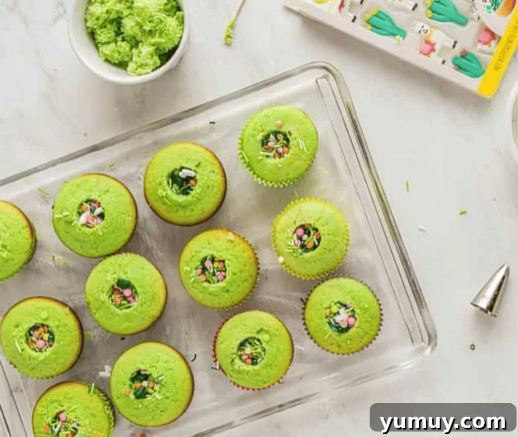 Cinco de Mayo Fiesta Cupcakes 9 cored green cupcakes with colorful sprinkles visible in the center, arranged on a wire rack.