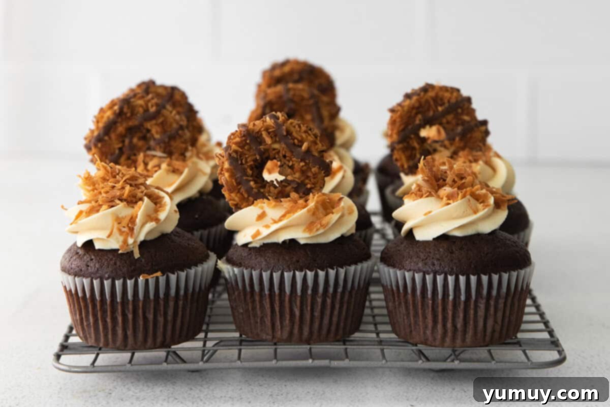 Caramel Coconut Chocolate Bliss Cupcakes 15 A charming collection of freshly frosted cupcakes, adorned with coconut and sea salt, resting on a wire rack.