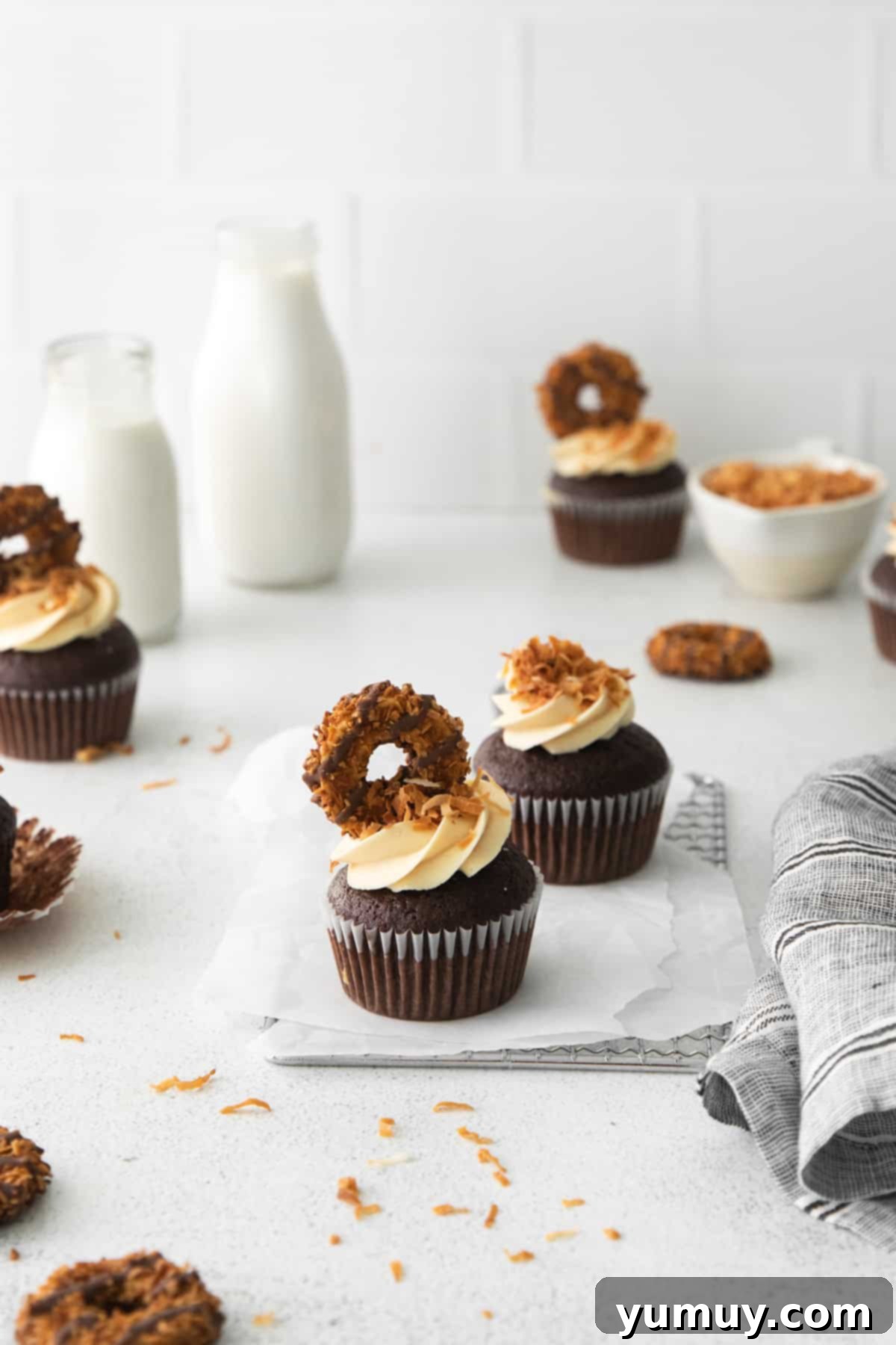 Caramel Coconut Chocolate Bliss Cupcakes 3 A charming arrangement of Samoa-inspired cupcakes on a table, perfectly paired with a refreshing glass of milk.