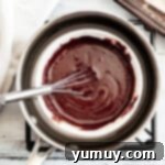 Melted chocolate mint coating in a bowl, being whisked to achieve a smooth, glossy consistency.