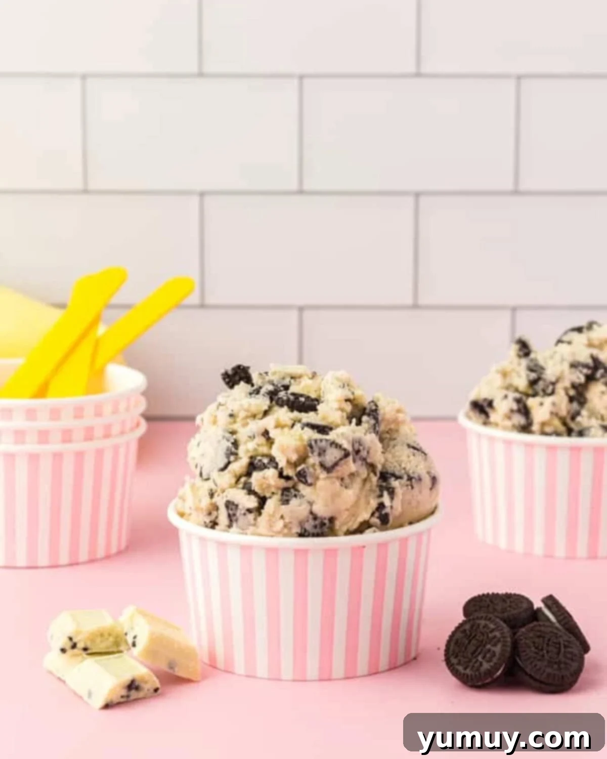 Safe-to-Eat Oreo Cookie Dough 2 Side view of servings of Oreo cookie dough piled into pink and white striped paper cups.