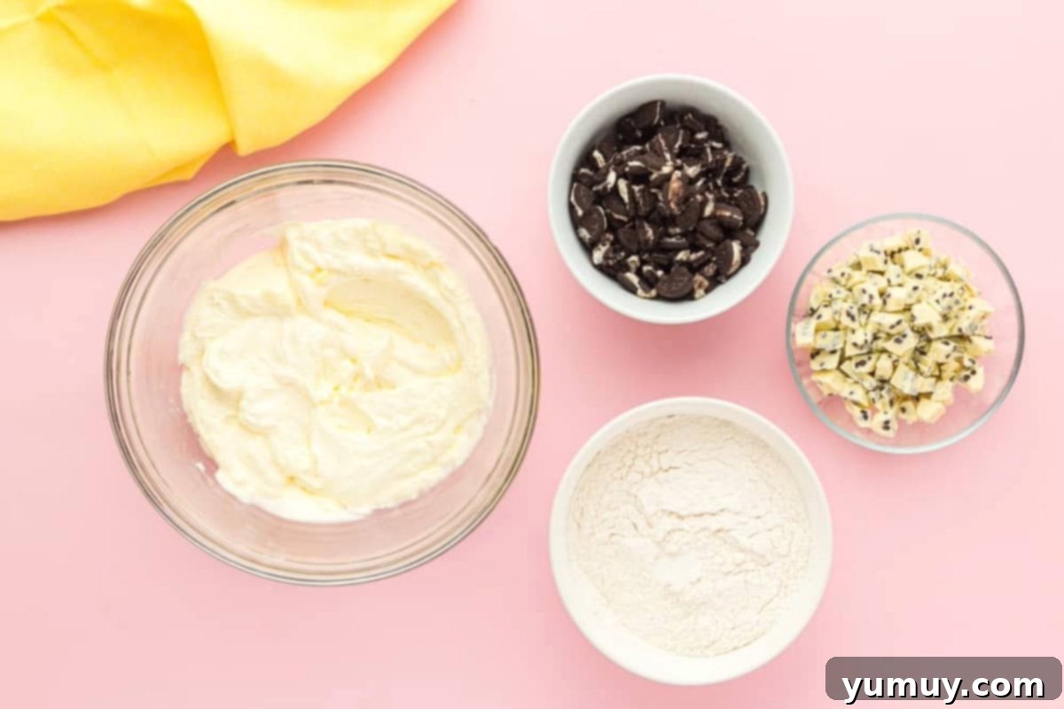 Safe-to-Eat Oreo Cookie Dough 9 Creamed butter and sugar in a glass bowl next to bowls of flour, chopped cookies, and chopped white chocolate candy bars.