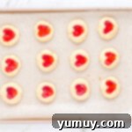 Heart Kiss Cookies 13 12 heart thumbprint cookies on a baking sheet.