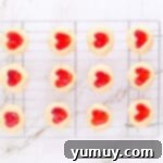 Heart Kiss Cookies 14 12 heart thumbprint cookies on a wire cooling rack.