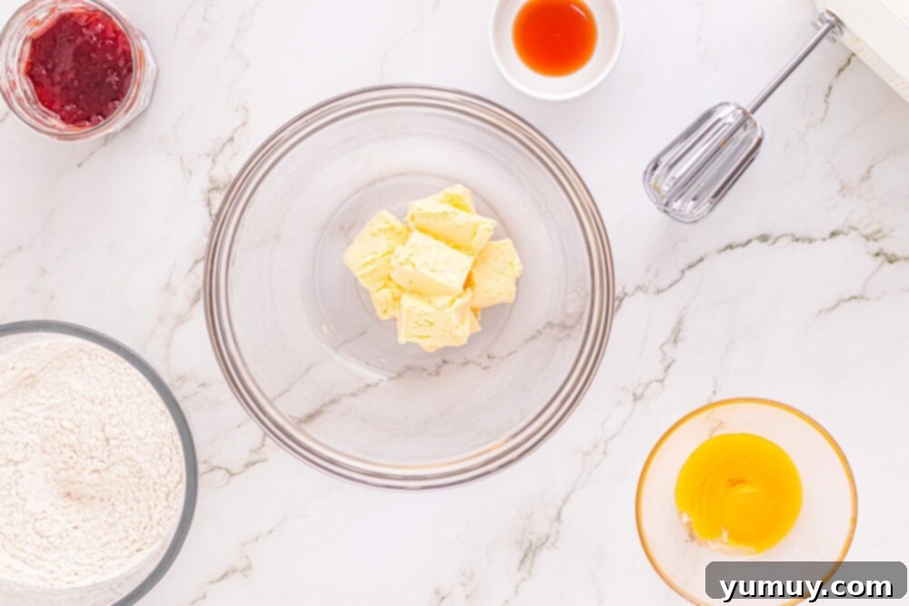 Heart Kiss Cookies 15 Close-up of softened, beaten butter in a clear glass mixing bowl, ready for the next ingredients.