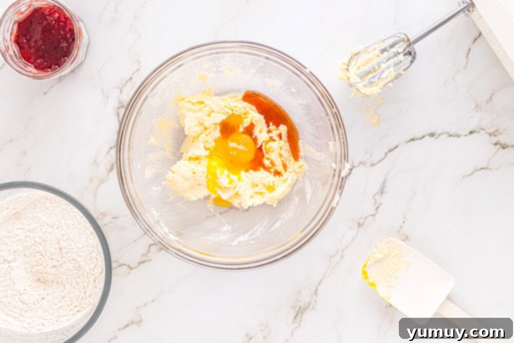 Heart Kiss Cookies 16 Wet ingredients (butter, sugar, egg yolks, vanilla) for heart thumbprint cookies combined in a glass mixing bowl, showing a smooth, creamy texture.