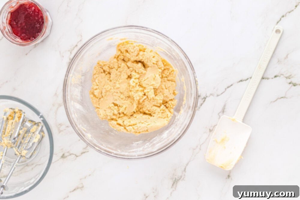 Heart Kiss Cookies 18 Heart thumbprint cookie dough resting in a glass bowl, covered with plastic wrap, chilling in the refrigerator.