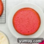 A leveled pink velvet cake layer positioned on a white cake stand, secured with a thin layer of frosting.